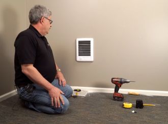 A Cadet staff member installing a wall heater