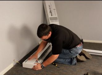 A Cadet staff member installing a Softheat baseboard heater