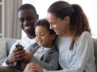 A family cuddled up warm and cozy on their couch at home