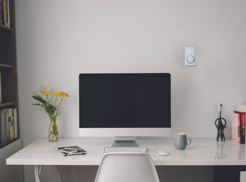 thermostat on wall above computer desk