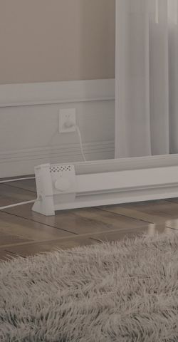 A living space with a Cadet Portable Baseboard heater plugged into the wall