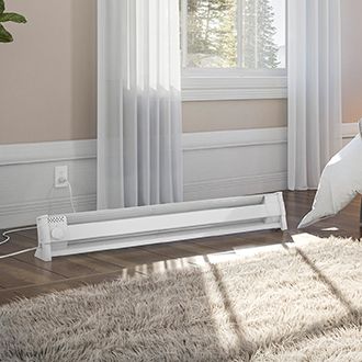 A living space with a Cadet Portable Baseboard heater plugged into the wall