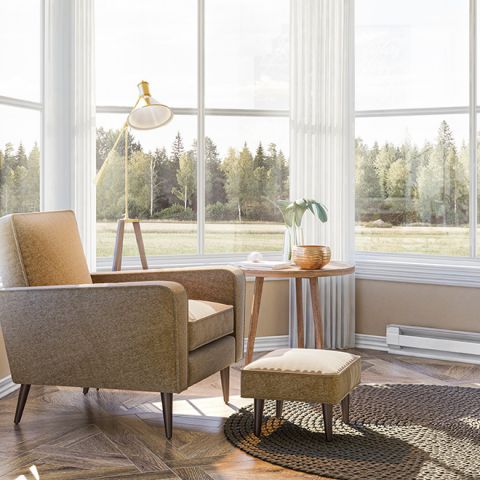 A living room with large windows and limited wall space with a baseboard heater mounted to the skirting board