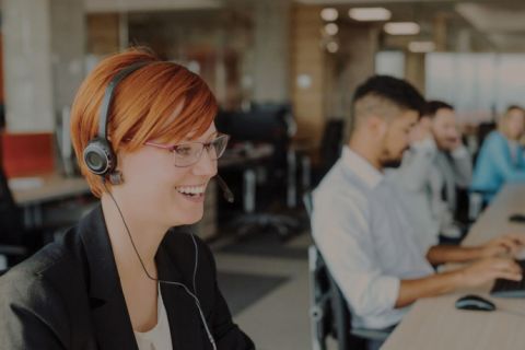 A row of customer service representatives sitting at desks answering phone calls