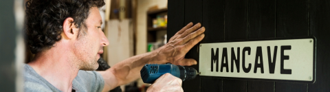 Man installing a man cave sign on the door to his updated garage with cadet garage heaters.